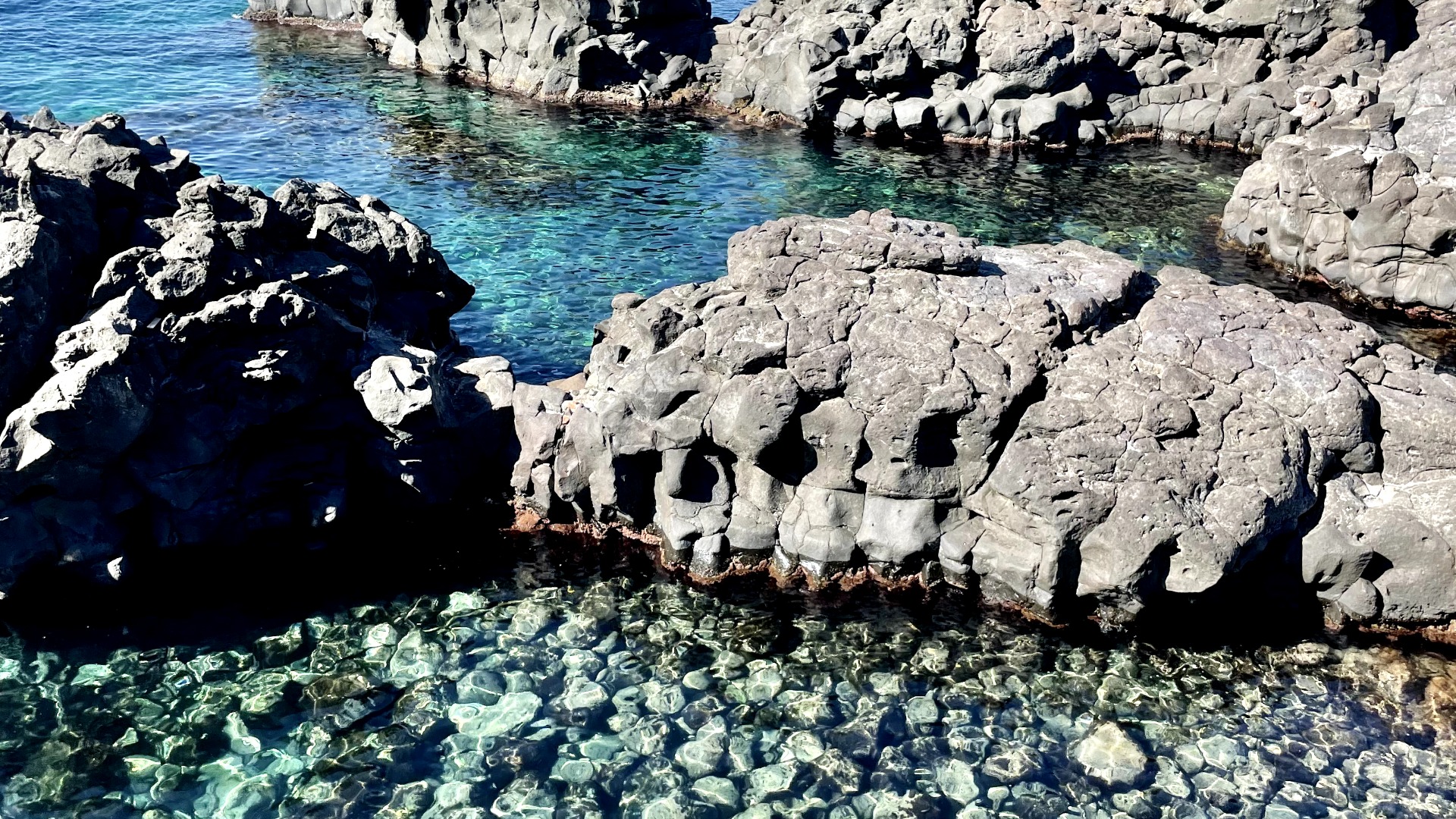 La scogliera lavica del Lido Grotta Smeralda con acqua smeralda ad Acicastello